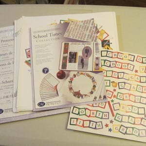 Puede incluir: Un conjunto de suministros de scrapbooking con temática escolar, que incluye protectores de página, pegatinas y fichas de letras. Las pegatinas presentan palabras como "School Days", "Kindergarten" y "First Grade".