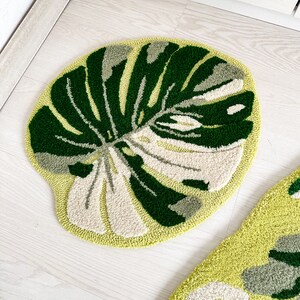 May include: Two round green and white rugs with a leaf design. The rugs are on a white wood floor.