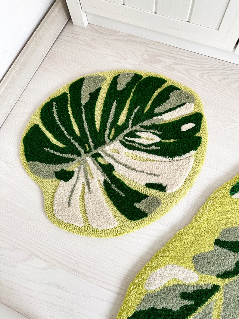 May include: Two round green and white rugs with a leaf design. The rugs are on a white wood floor.