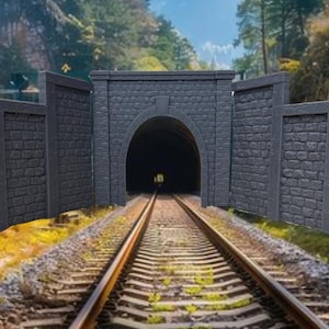 May include: A model train tunnel entrance with stone walls and a dark opening. The tunnel is set on a model railroad track with brown gravel and green foliage.