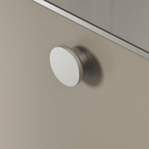 May include: Close-up of two cabinet drawers with round, silver and white knobs. The drawers are a neutral beige colour, and the knobs have a modern, minimalist design. The knobs are slightly raised from the drawer surface.