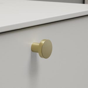 May include: A white cabinet with a gold-coloured, round knob. The cabinet is part of a bathroom vanity. A bottle of lotion and a tube of cream are on the white countertop.