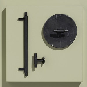 May include: Four black cabinet hardware pulls, including a long bar pull, a small knob, and two round knobs with a black marble design.