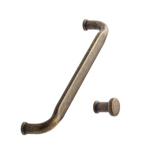 May include: Antique brass cabinet pull with a curved design and a matching knob. The pull is approximately 25 cm long.