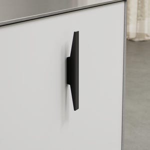 May include: A close-up of a modern cabinet with a matte white finish. A sleek, black handle is mounted on the cabinet door. The handle has a minimalist design, with a rectangular shape that tapers towards the bottom.