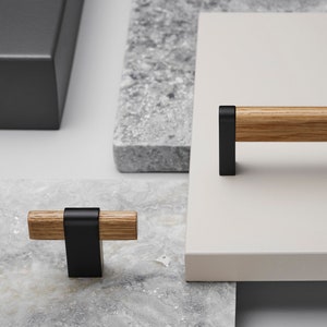 May include: Two cabinet pulls with a black metal frame and a wooden handle. The smaller pull is 7.6 cm long and the larger pull is 15.2 cm long.