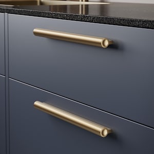 May include: A navy blue cabinet with two gold-coloured, cylindrical drawer pulls. The pulls are horizontally mounted and have a simple, modern design. The countertop is dark with a speckled pattern.