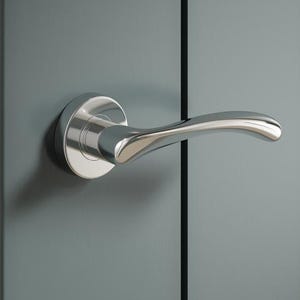 May include: A shiny chrome door handle with a curved lever and a circular base is fixed to a grey door. The door also has a gold-coloured latch plate. A white bedspread is partially visible in the background.