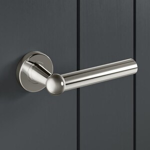 May include: A shiny chrome door handle with a circular base and a straight lever. The handle is fixed to a dark grey door with vertical grooves. The door is ajar, showing a peek of the interior.