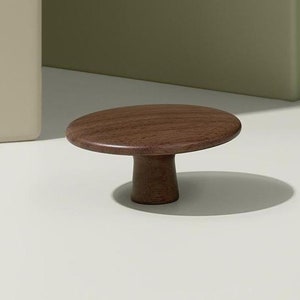 May include: A round, dark brown wooden knob with a mushroom-shaped design. The knob is made of solid wood and has a smooth, polished finish.