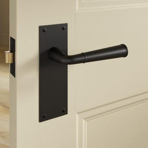 May include: A black door handle with a rectangular backplate is mounted on a cream-coloured door. The handle has a curved design and is made of metal. The door also features a gold-coloured door latch.