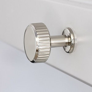 May include: A silver knob with a fluted design. The knob is attached to a metal post.