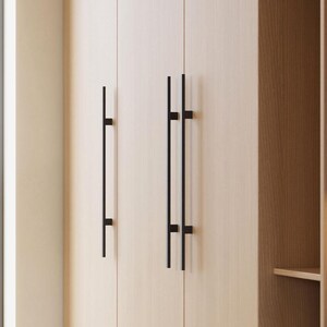 May include: A set of wooden cabinets with black metal handles. The cabinets have a light wood finish and are open to reveal shelves. The shelves are empty, but there is a lamp on one of the shelves.
