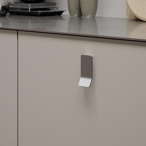 May include: A contemporary kitchen interior with a coffee brewing station, including a glass carafe and a pour-over system. The beige cabinets have silver handles. A wooden chopping board and small ceramic cups contribute to the minimalist design.