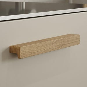 May include: A wooden cabinet pull with a rectangular shape and a natural wood finish.