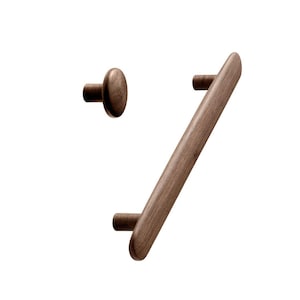 May include: Two wooden cabinet knobs, one round and one long and rectangular. The round knob is brown and has a smooth surface. The long knob is also brown and has a smooth surface. Both knobs are made of wood.