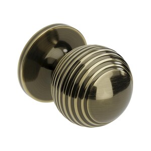 May include: A bronze door knob with a ribbed, spherical handle and a circular backplate. The knob has a vintage appearance and is likely made of metal. The design features parallel grooves around the spherical handle, suitable for a door.