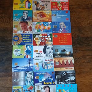 Peut inclure: Collection de cartes téléphoniques françaises vintage, présentant divers designs et publicités. Les cartes présentent des images de personnes, de produits et de texte, avec une variété de couleurs et de styles. Certaines cartes ont le texte "Telecarte 50" et "Telecarte 120".
