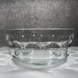 Puede incluir: Una taza de cerámica blanca con un asa negra y el texto "But First, Coffee" en negro, en negrita. La taza está sobre una superficie blanca.