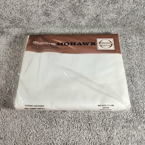 May include: A packaged white Stevens Mohawk fine combed percale sheet. The packaging is clear plastic with a brown and white label. The label reads "Stevens Mohawk" and "Fine Combed Percale". The sheet measures 72 x 108 inches.