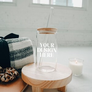 May include: A clear glass jar with a wooden lid and a straw. The jar has the text "YOUR DESIGN HERE" printed on it. The jar is sitting on a wooden stand next to a white candle and a black and white blanket.