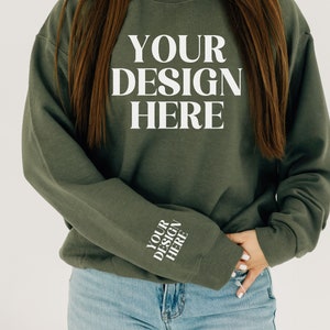 May include: A green sweatshirt with the text "YOUR DESIGN HERE" on the front and the same text on the left sleeve.