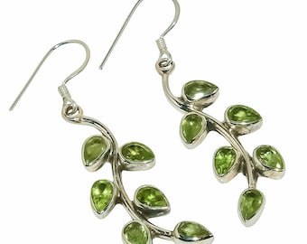 May include: Silver earrings with a delicate branch design and green gemstones. The earrings have a hook closure.