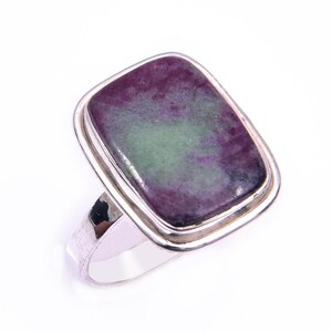 Pode incluir: Um anel de prata com uma grande pedra preciosa retangular polida de superfície lisa. A pedra apresenta um padrão marmoreado em tons de magenta profundo e verde suave, engastada numa moldura de prata polida simples e uma banda lisa.