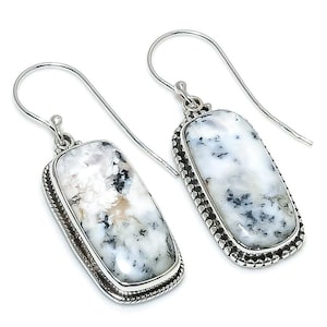 May include: A pair of rectangular drop earrings featuring white dendritic opal stones with black fern-like inclusions. The stones are set in polished silver frames with a beaded edge detail and attached to simple silver shepherd hook ear wires.