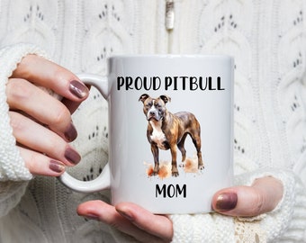 May include: White ceramic coffee mug with a brown and white pitbull dog illustration. The mug has the text "Proud Pitbull Mom" printed on it.