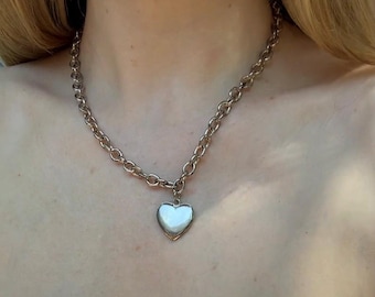 May include: A silver chain necklace with a heart-shaped pendant.