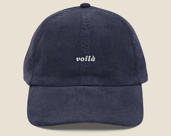 Op de afbeelding: Marineblauwe corduroy baseballcap met het woord "voilà" in het wit geborduurd. De cap heeft een gebogen klep en een ronde kroon. Een casual accessoire voor dagelijks gebruik.
