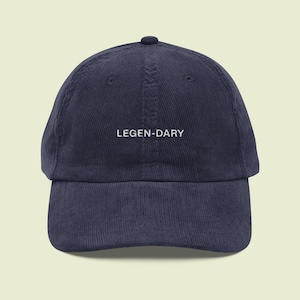 May include: Navy blue corduroy baseball cap with the word "LEGEN-DARY" embroidered in white. The cap has a curved brim and a rounded crown. A stylish and comfortable accessory.