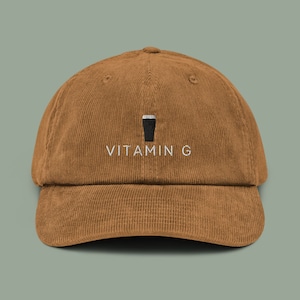 Könnte beinhalten: Eine braune Baseballkappe aus Cord mit einem weißen gestickten Design eines Bierglases und dem Text "VITAMIN G".
