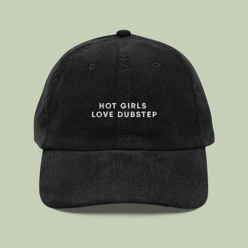 Op de afbeelding: Zwarte corduroy baseballpet met witte geborduurde tekst die "HOT GIRLS LOVE DUBSTEP" zegt.