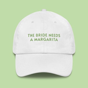 May include: White baseball cap with green embroidered text that reads "The Bride Needs a Margarita".