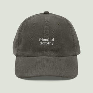 Può includere: Cappellino da baseball in velluto a coste verde oliva con la scritta bianca "friend of dorothy" ricamata. Il cappellino ha una visiera curva e una parte superiore arrotondata. Un accessorio casual.