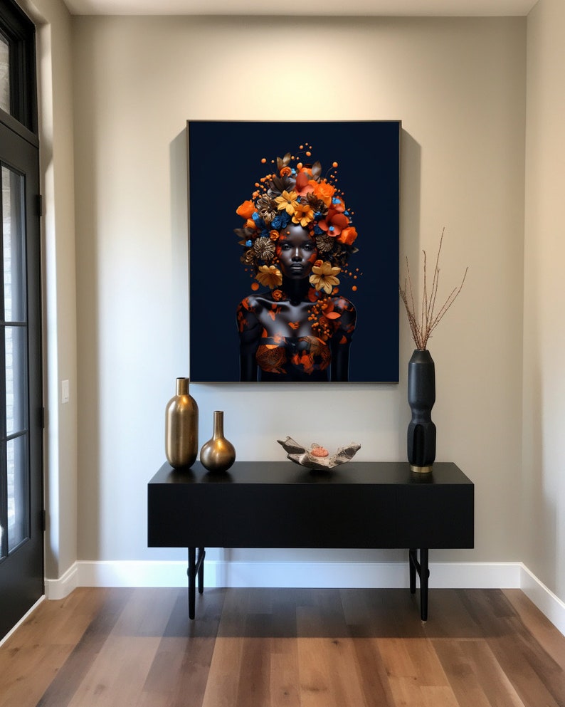 Peut inclure: Un portrait en noir et blanc d'une personne avec une couronne de fleurs orange, brunes et bleues sur la t&ecirc;te. Le portrait est accroch&eacute; au mur au-dessus d'une console noire avec deux vases dor&eacute;s et un objet d&eacute;coratif.