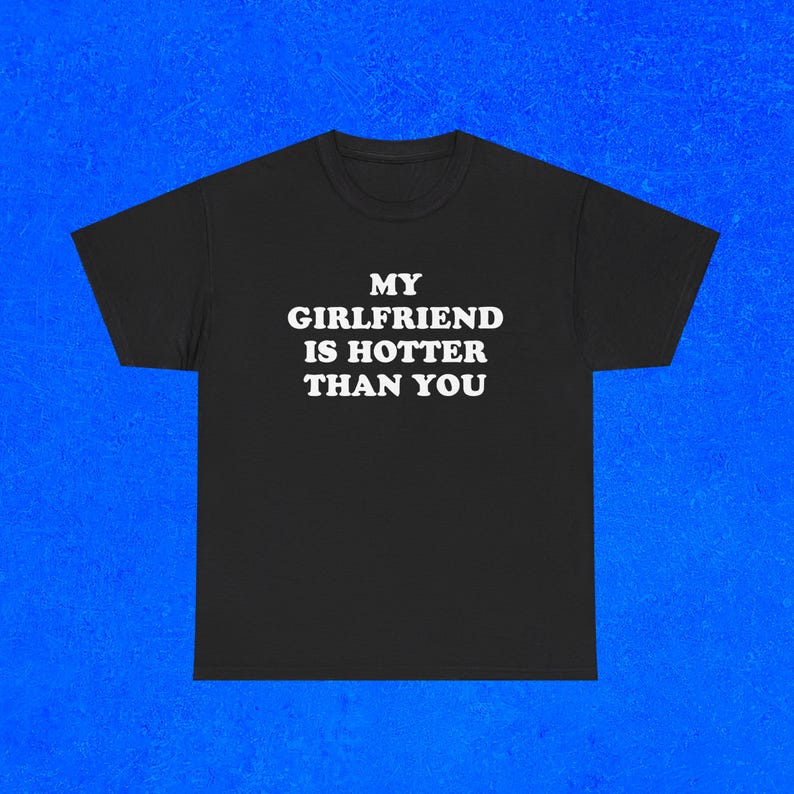 Pu&ograve; includere: T-shirt nero con la scritta bianca "MY GIRLFRIEND IS HOTTER THAN YOU". La maglietta ha girocollo e maniche corte. Lo sfondo &egrave; di colore blu.