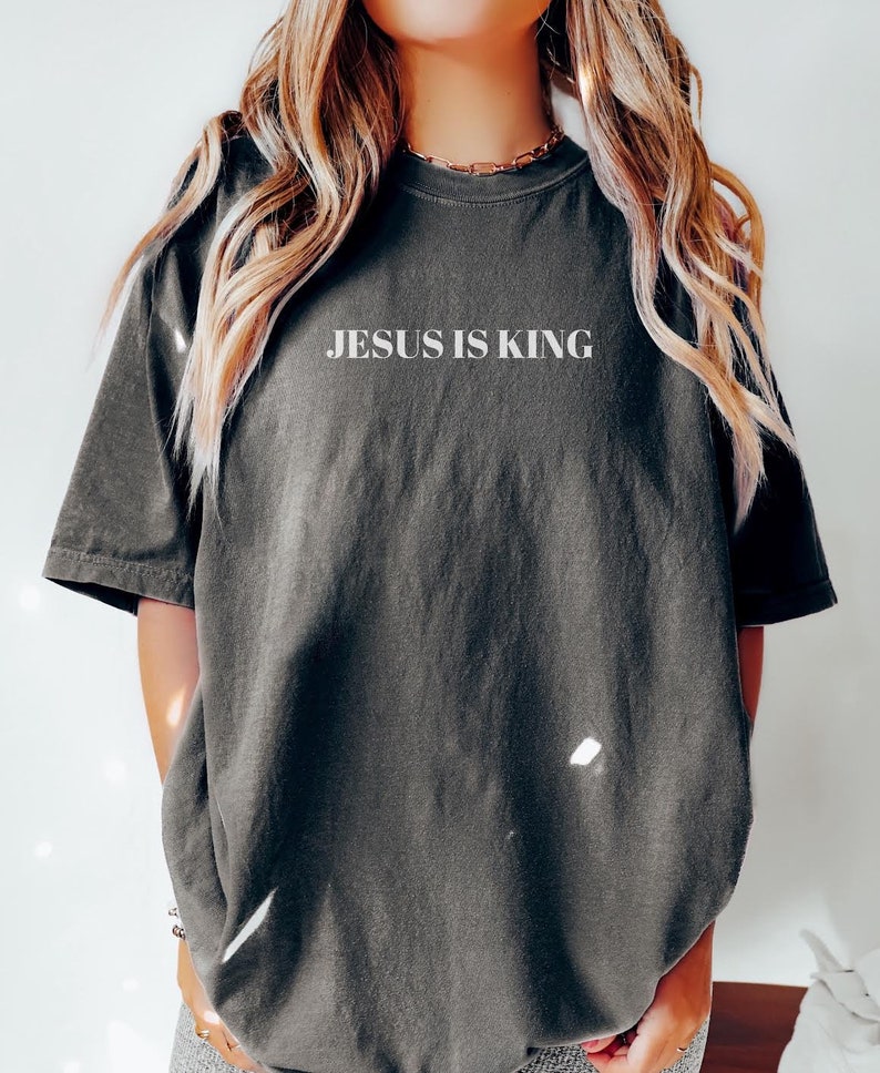 K&ouml;nnte beinhalten: Ein &uuml;berdimensioniertes T-Shirt in dunkelgrau mit dem Aufdruck "JESUS IS KING" in wei&szlig; auf der Vorderseite.