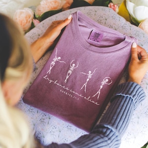 May include: Purple t-shirt with a white graphic of skeletons dancing and the text "dry bones come alive Ezekiel 37:3"