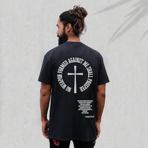 Pode incluir: Camiseta preta com um gr&aacute;fico circular branco nas costas. O gr&aacute;fico apresenta uma cruz e o texto "No weapon formed against me shall prosper." O texto "And every tongue which riseth against thee in judgment thou shalt condemn. This is the heritage of the servants of the Lord, and their righteousness is of me, saith the Lord." est&aacute; impresso abaixo do gr&aacute;fico. O texto "Isaiah 54:17" est&aacute; impresso abaixo da cita&ccedil;&atilde;o.