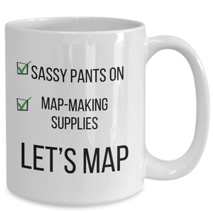 May include: White ceramic coffee mug with black text that reads "Sassy Pants On", a green checkmark, "Map-Making Supplies", a green checkmark, and "Let's Map".