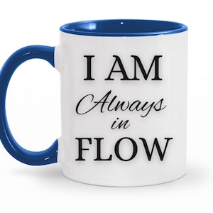 May include: White ceramic mug with a blue handle and interior. The mug features the text "I AM Always in FLOW" in black, with the words "Always" and "in" in a cursive font. The mug is designed for hot beverages.