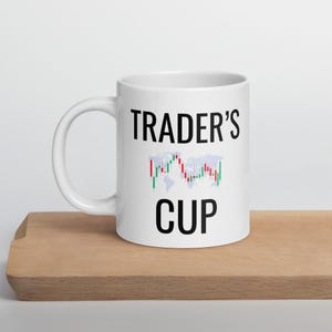 May include: White ceramic mug with a black graphic that says "TRADER'S CUP" and a stylized image of a world map with red and green candlestick charts.
