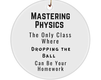 May include: White ceramic ornament with black text that reads "Mastering Physics. The Only Class Where Dropping The Ball Can Be Your Homework."