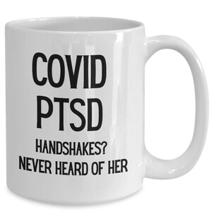 Könnte beinhalten: Eine weiße Keramik-Kaffeetasse mit schwarzem Text, der "COVID PTSD HANDSHAKES? NEVER HEARD OF HER" lautet