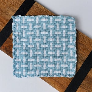 May include: A blue and white woven kitchen dishcloth with a square shape and a fringed edge.