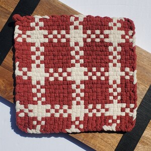 May include: Red and white woven pot holder with a geometric pattern. The pot holder is made of a thick, durable material and is perfect for protecting your hands from hot surfaces.