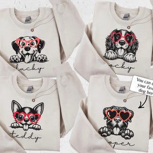 May include: Beige sweatshirts featuring dog illustrations wearing heart-shaped glasses. Each sweatshirt has a different dog breed with a name below. The text on the image says, "You can choose your favorite dog breed."